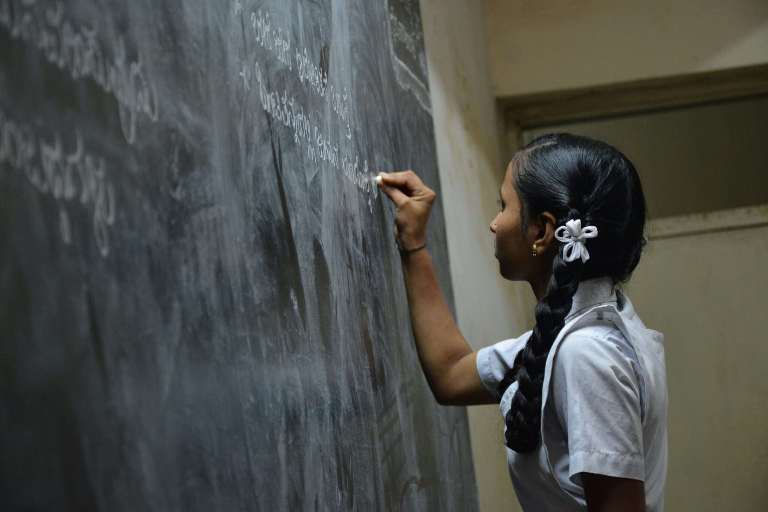 Girl standing writes on a chalkboard.